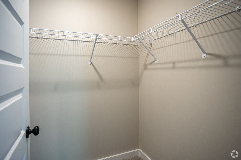 a walk in closet with empty shelves and a door