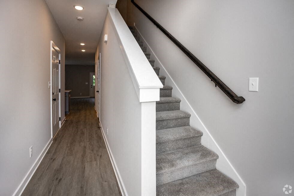a gray carpeted staircase in a house with a white wall