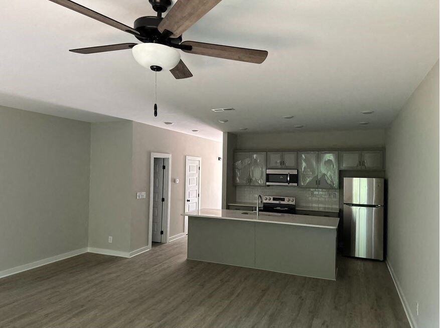 a living room with a kitchen and a ceiling fan