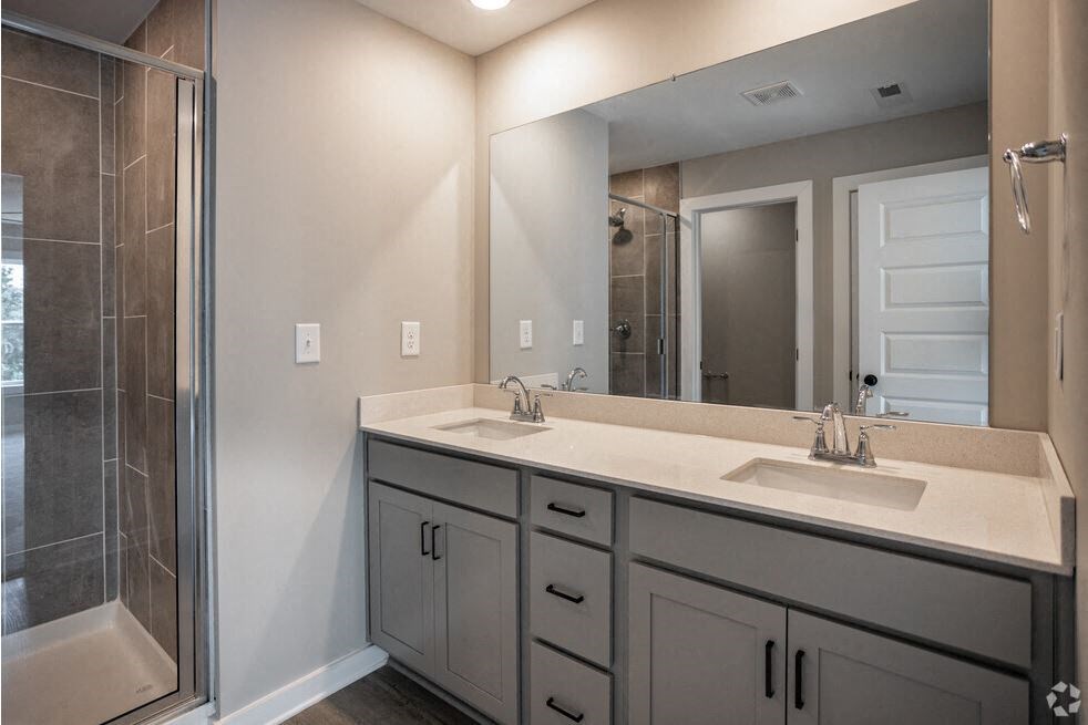 a bathroom with two sinks and a shower and a mirror