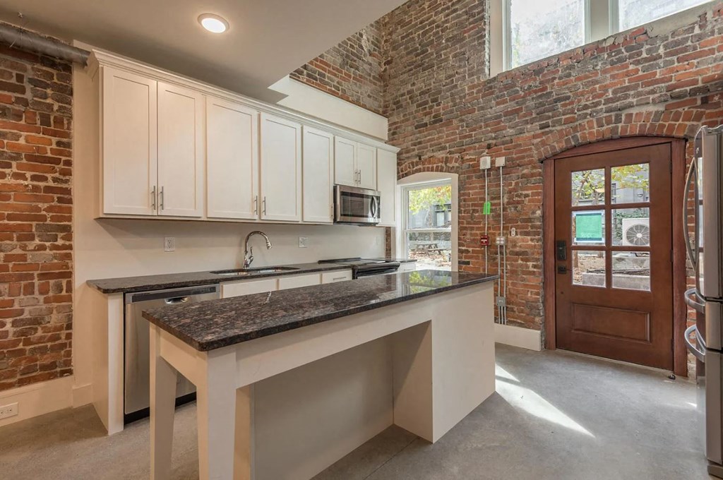 a kitchen with a long counter and a brick wall