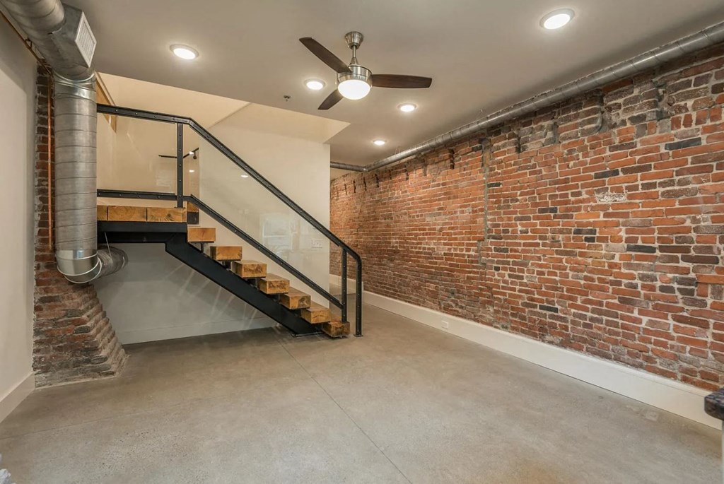 a brick walled room with a staircase and a ceiling fan