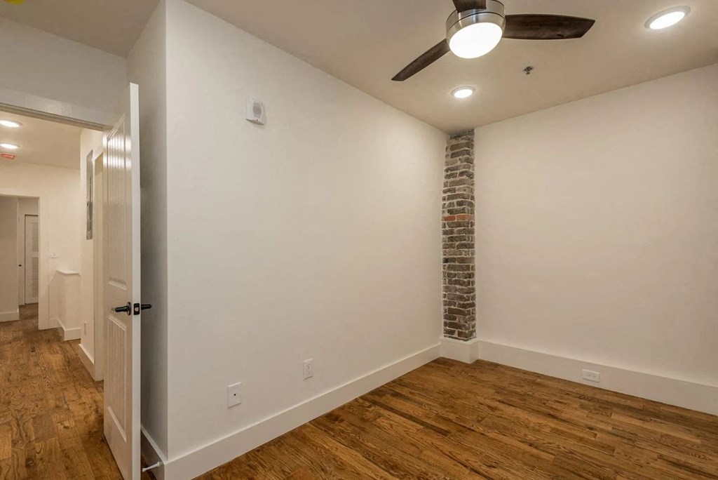 a bedroom with a ceiling fan and a brick accent wall