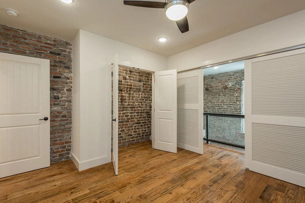 a bedroom with a brick wall and wood floors