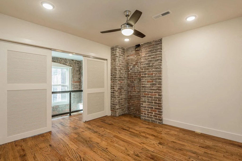 an empty room with a brick wall and a ceiling fan