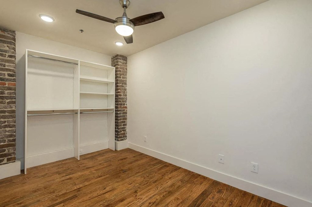 a bedroom with white walls and a ceiling fan