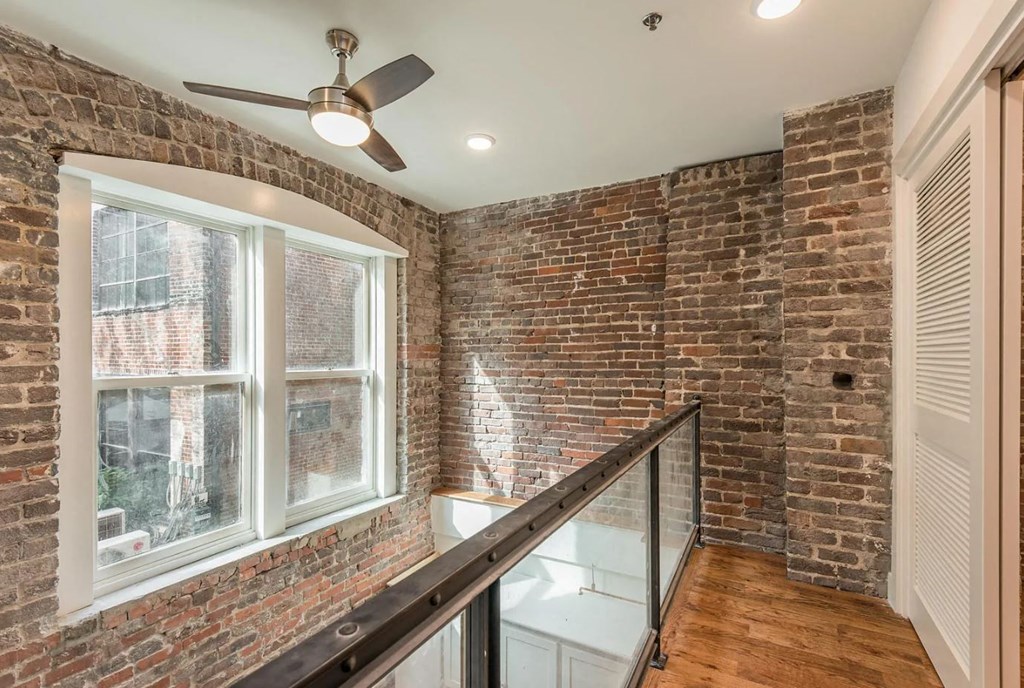 a brick walled room with a large window and a rail in front of it