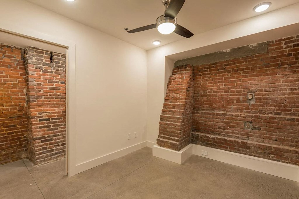 a room with a brick wall and a ceiling fan