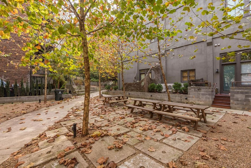 a courtyard with benches and trees in front of a building