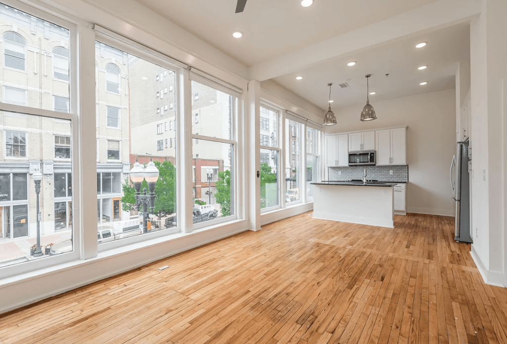 a living room with a large window and hardwood floors