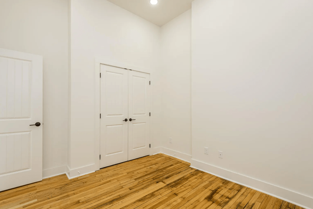 a bedroom with two doors and a hardwood floor
