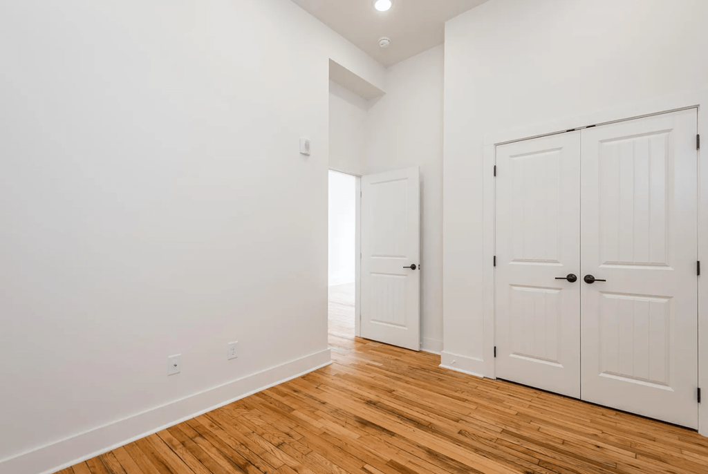 a bedroom with white walls and a hardwood floor