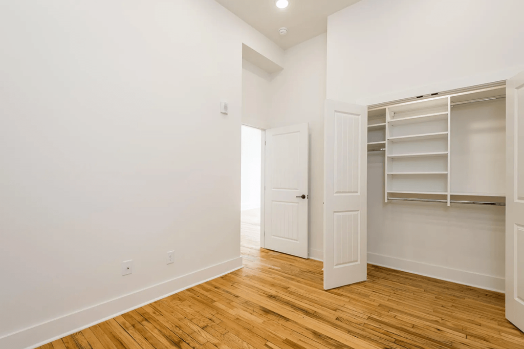 a bedroom with a medium hardwood floor and white walls
