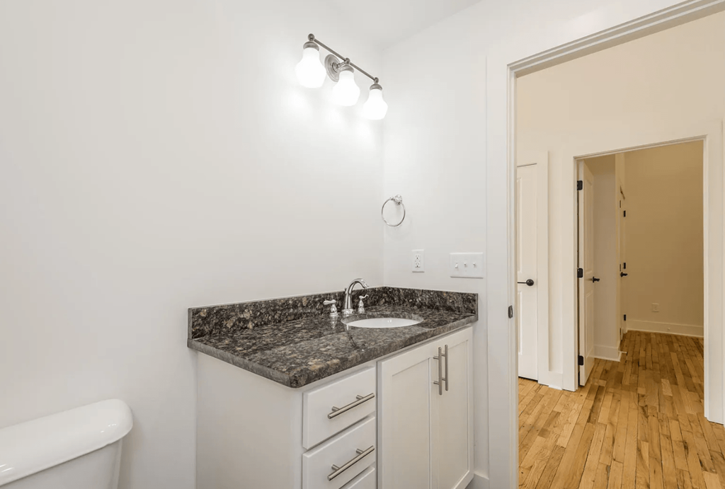 a bathroom with white walls and a granite counter top