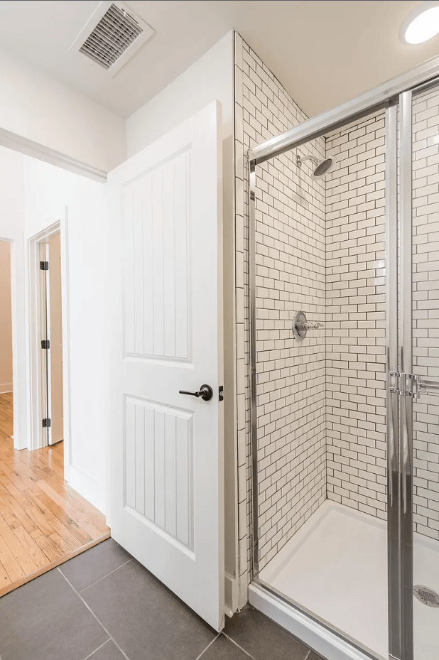 a bathroom with a white door and a shower with a glass door
