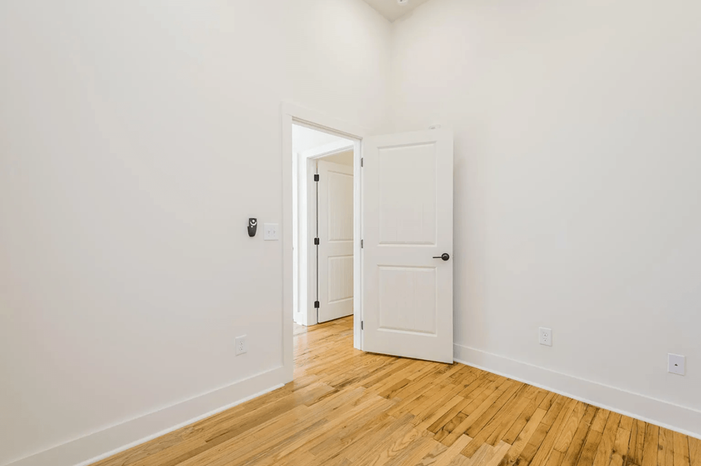 a bedroom with white walls and hardwood floors