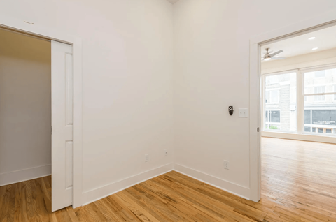 a living room with white walls and wood floors and a doorway