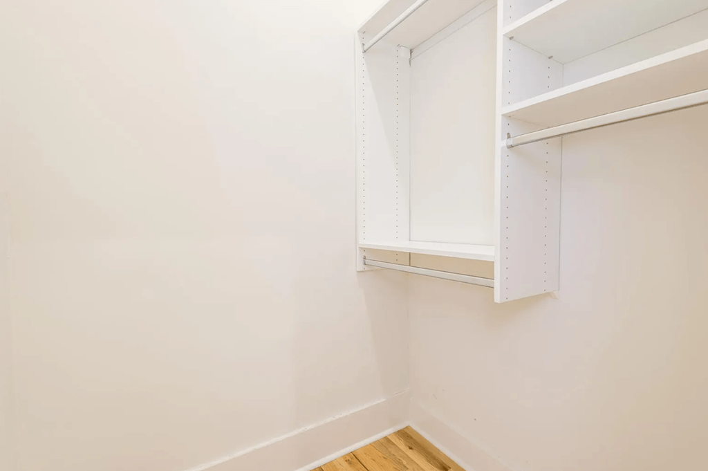 a small closet with white walls and white shelves