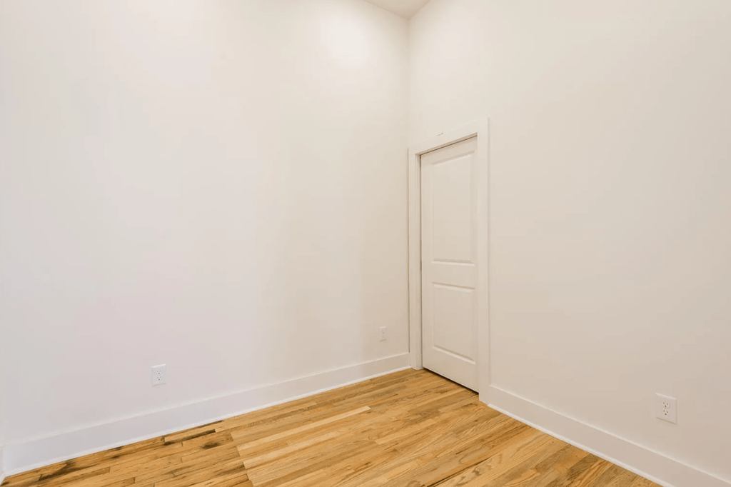 a bedroom with white walls and a wooden floor