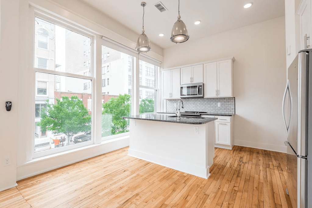 an open kitchen with a large window and hardwood floors
