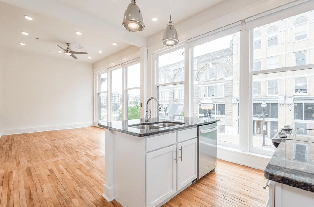 a kitchen with a large window and hardwood floors