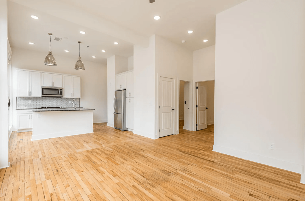 a kitchen and living room with hardwood floors and white walls