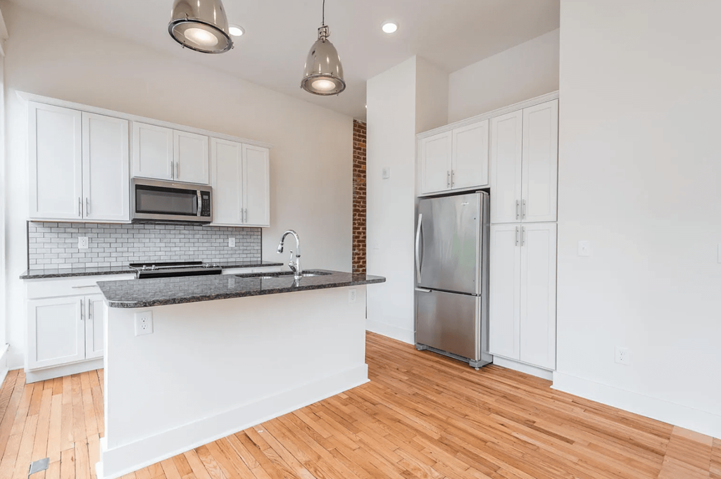 a kitchen with white cabinets and a black counter top