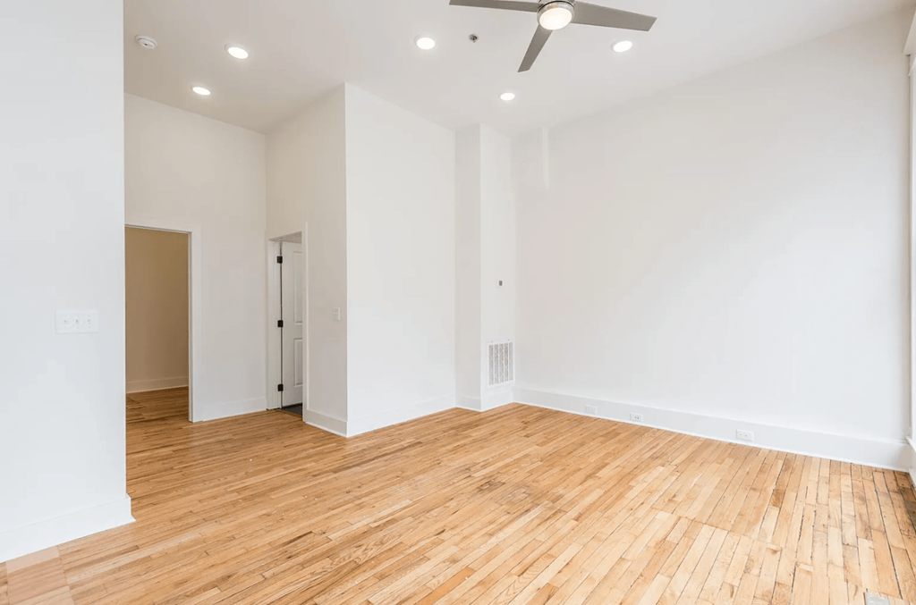 a bedroom with hardwood floors and white walls
