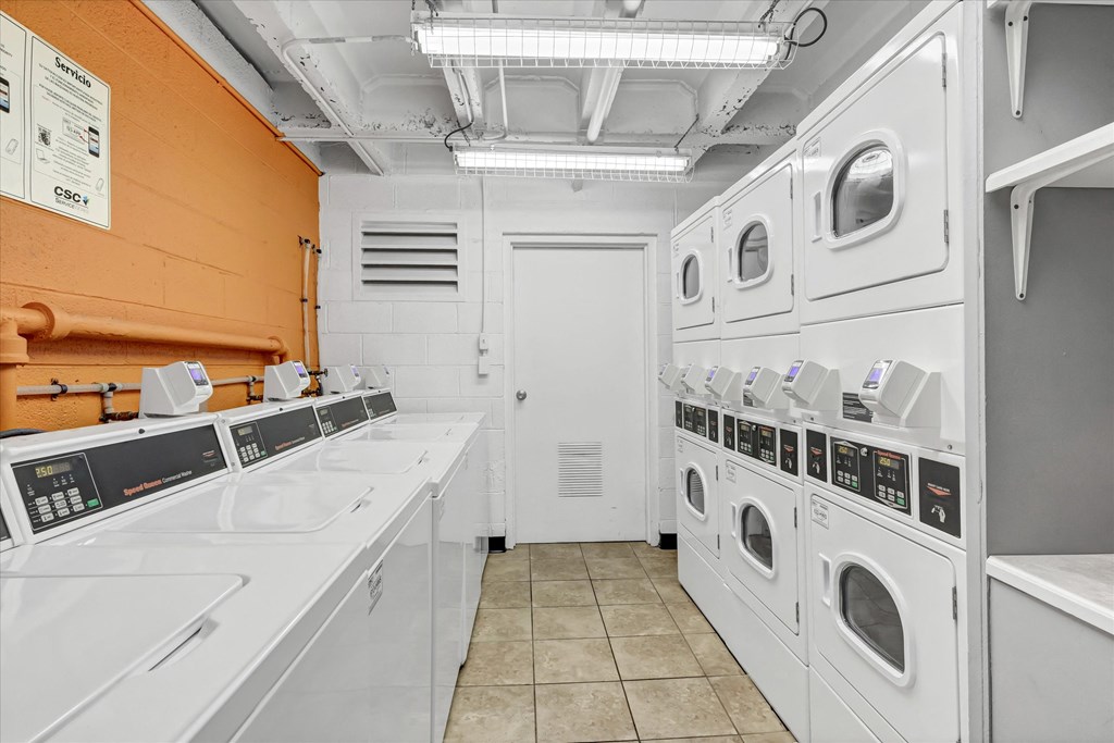a laundry room with washers and dryers and a row of washing machines