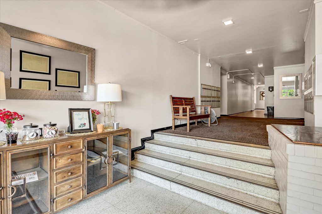 a living room with a staircase and a table with a mirror