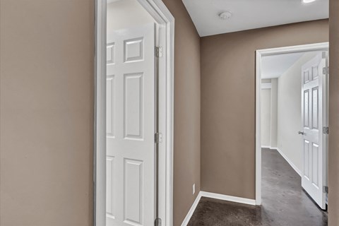 an open bedroom door with a hallway to a closet and a door to a bathroom