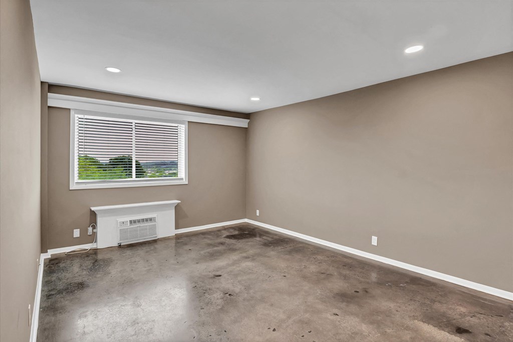 an empty living room with a window and a concrete floor