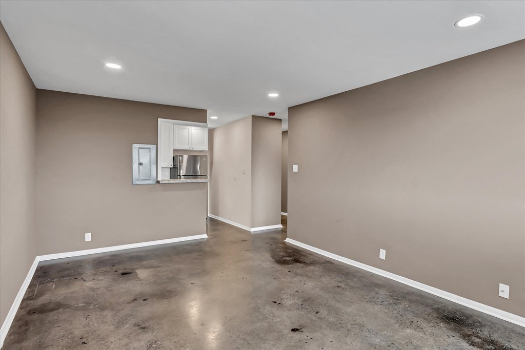 a empty room with a concrete floor and a kitchen