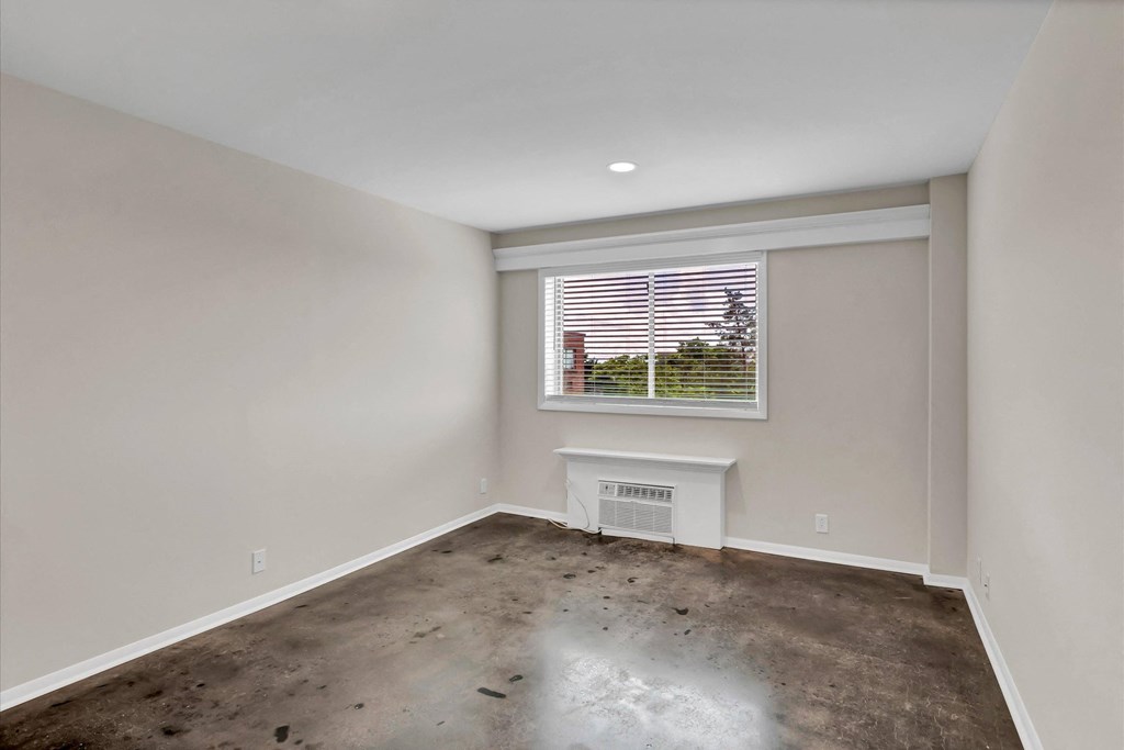 a living room with a window and a concrete floor