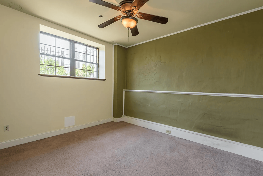 an empty room with a ceiling fan and a window