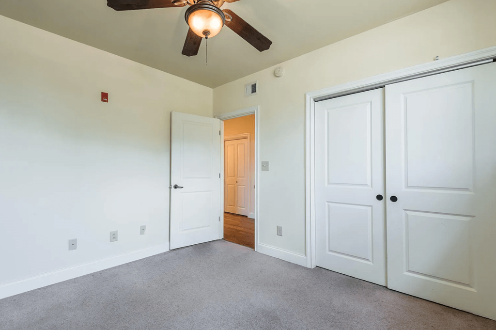 a bedroom with two closets and a ceiling fan