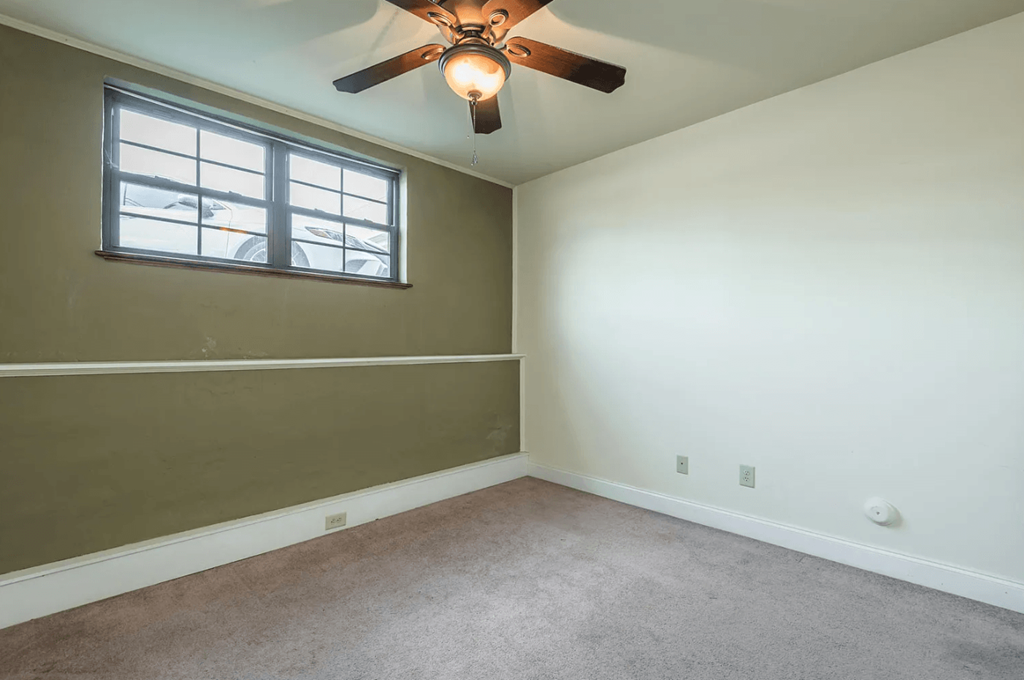 a bedroom with white walls and a ceiling fan