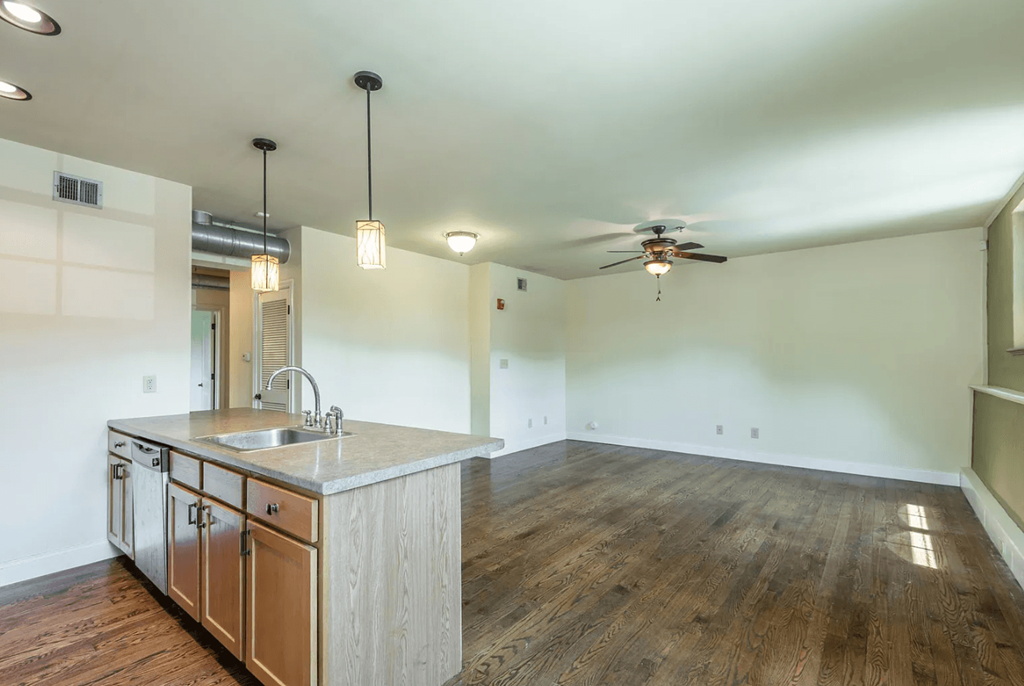 a kitchen and living room with white walls and a ceiling fan