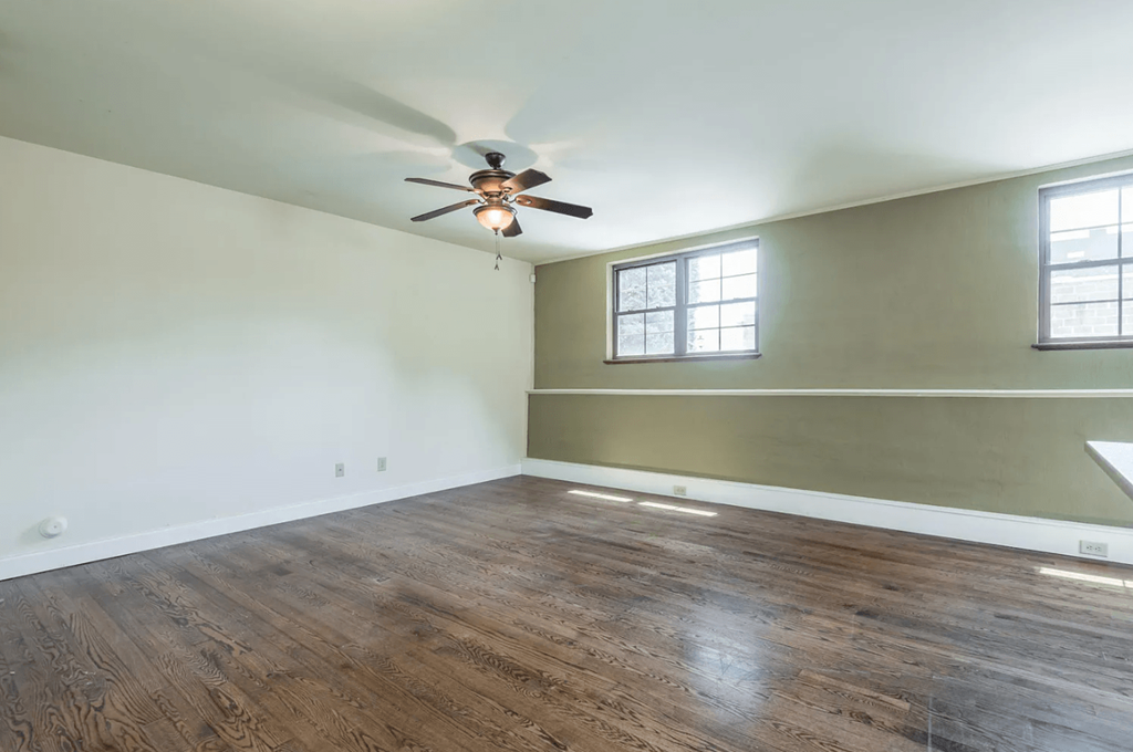 an empty room with a ceiling fan and a window