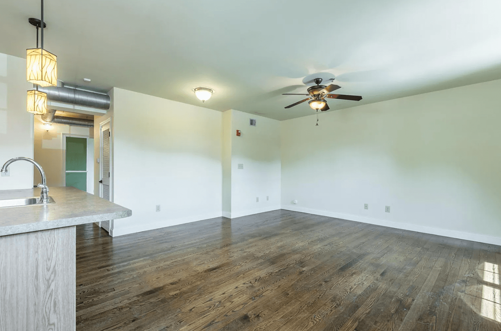 an empty living room with white walls and a ceiling fan