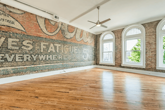 an old mural on a brick wall in an empty room with hardwood floors and a ceiling