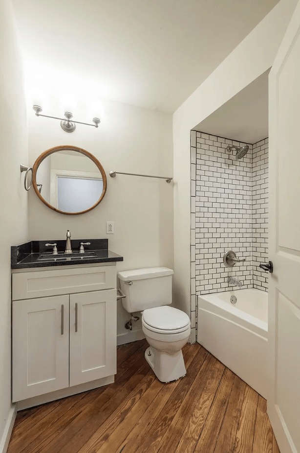 a bathroom with white walls and a wooden floor
