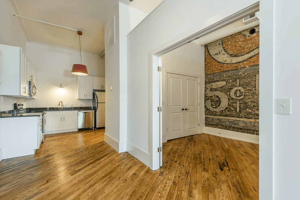 a kitchen and living room with hardwood floors and a exposed brick wall