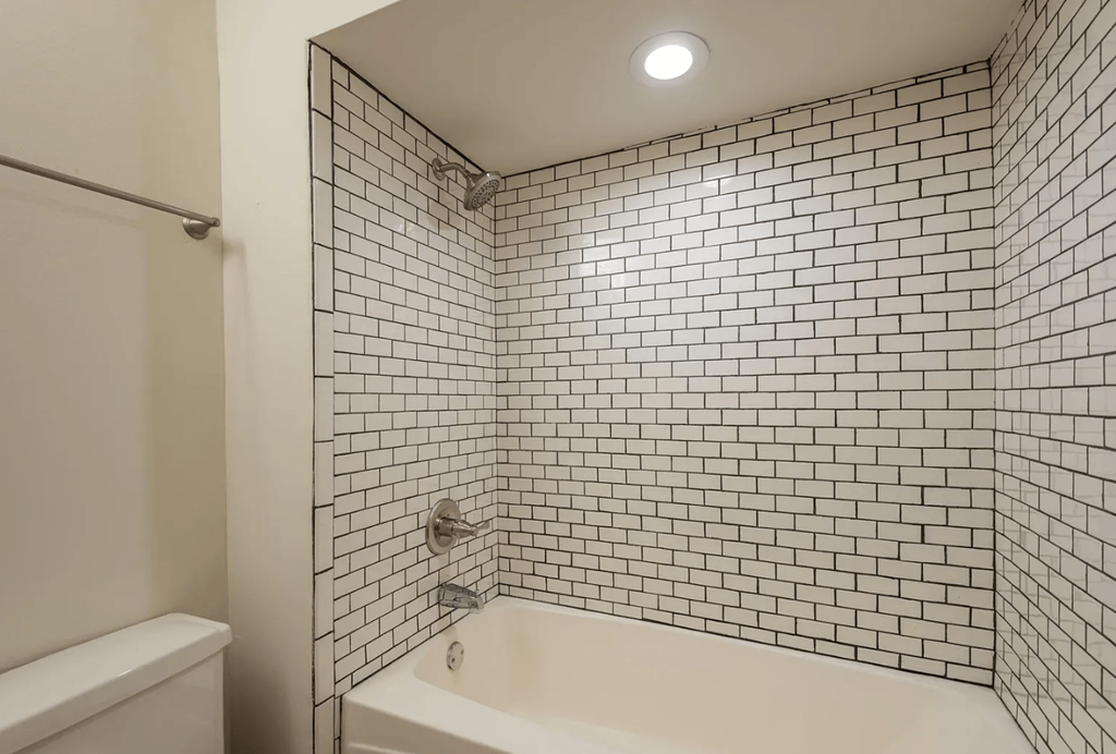 a bathroom with white tiles and a white bathtub