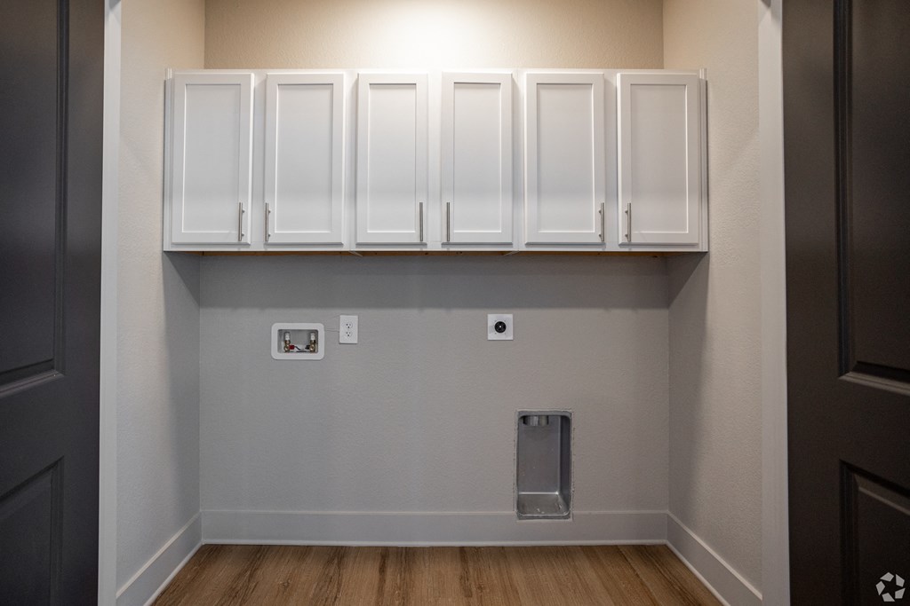 A kitchen with white cabinets and a trash can.