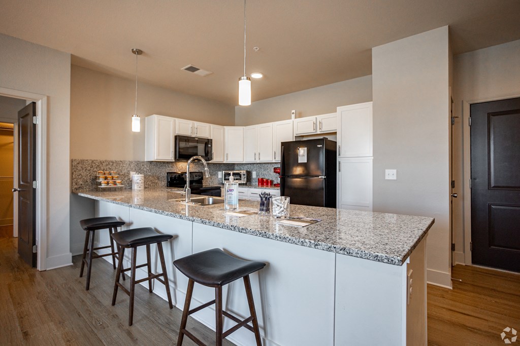 A kitchen with a granite countertop and white cabinets.