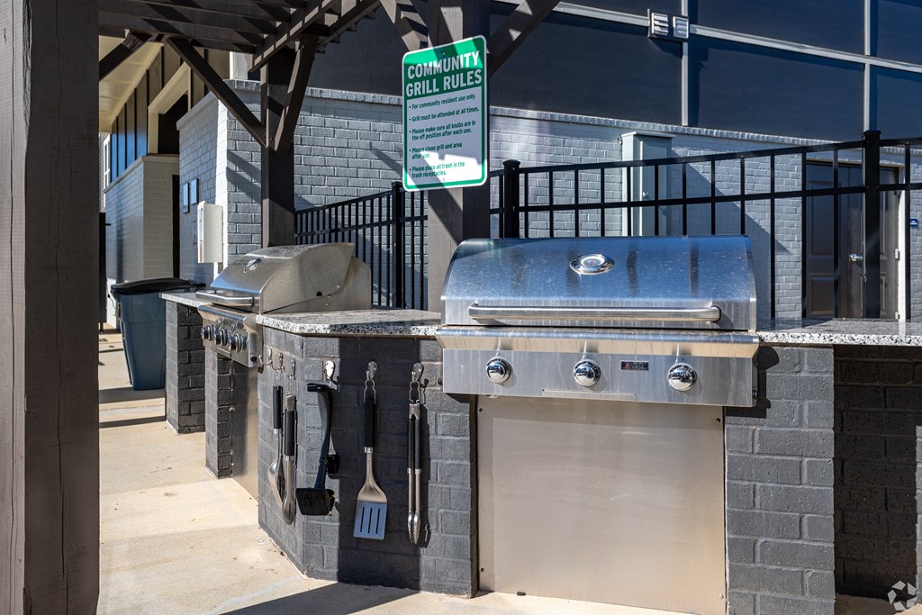 A sign that says "Community Grill Rules" hangs above a grill.