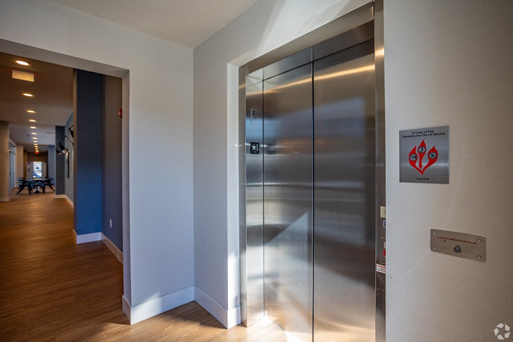 A stainless steel elevator with a red sign on the wall.