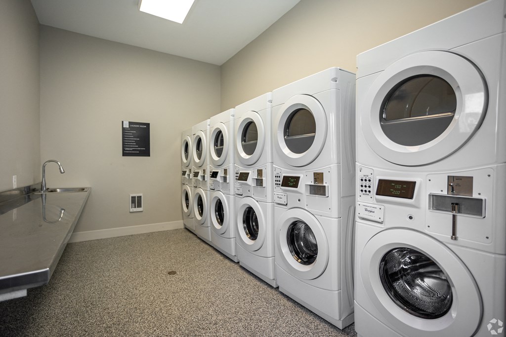 A row of white front load washing machines in a laundromat.
