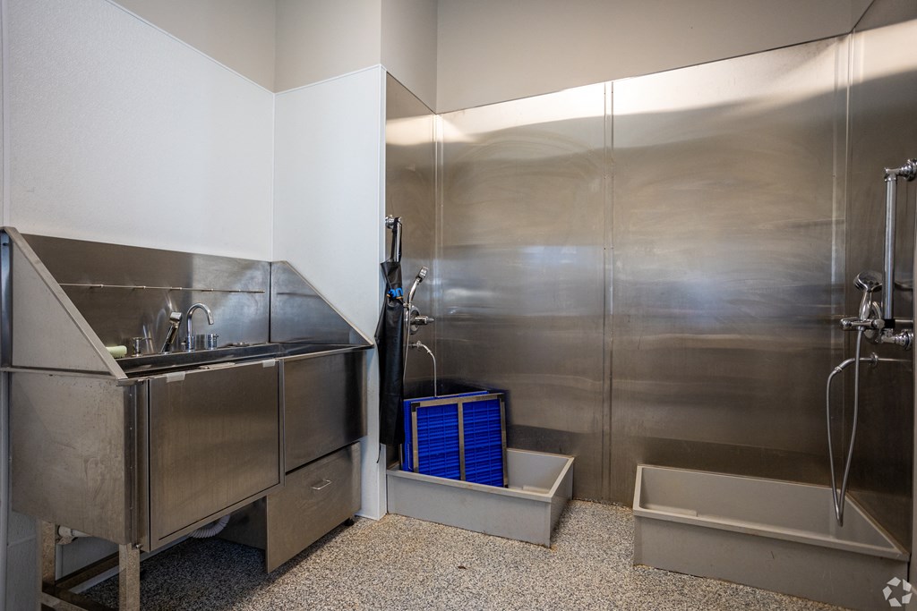 A stainless steel kitchen with a sink and a blue container.